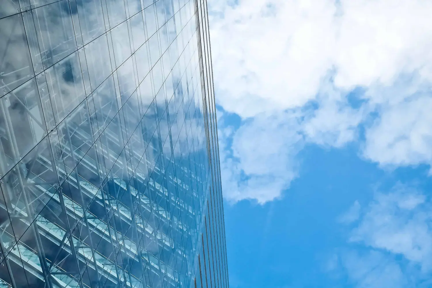 EMshield GmbH - Architecture and Corporate Security - The image displays a modern glass-clad skyscraper, showcasing architectural design and reflective surfaces.