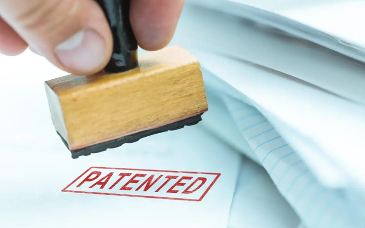 EMshield GmbH – Architektur und Unternehmenssicherheit – Das Bild zeigt einen Stempel, mit dem Dokumente als „PATENTIERT“ gekennzeichnet werden. Dies bedeutet, dass eine Erfindung oder ein Verfahren rechtlich geschützt ist.